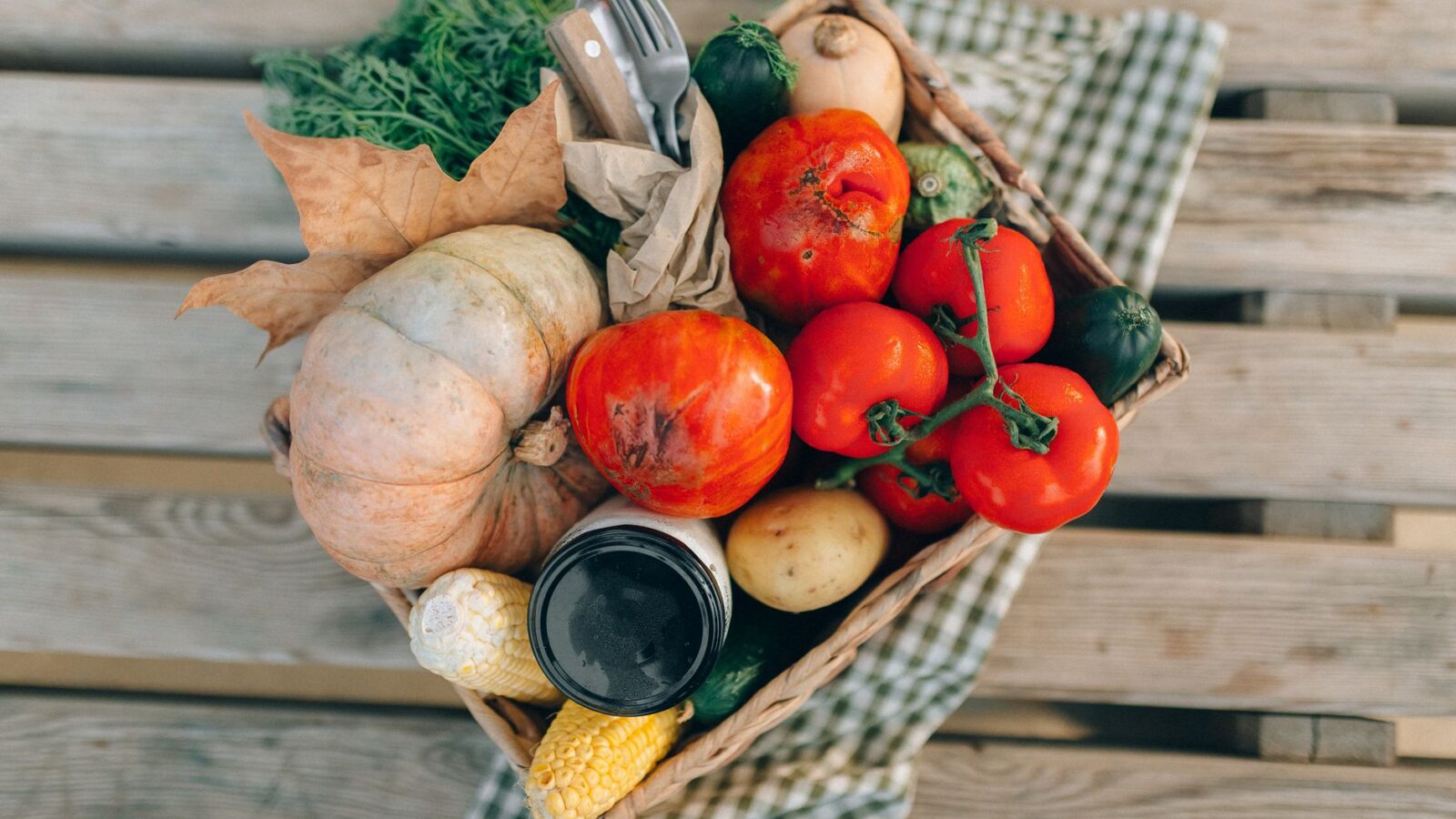 Wooden crates of winter squash, apples, and carrots stacked on a concrete garage floor near a thermometer.