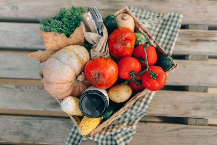 Wooden crates of winter squash, apples, and carrots stacked on a concrete garage floor near a thermometer.