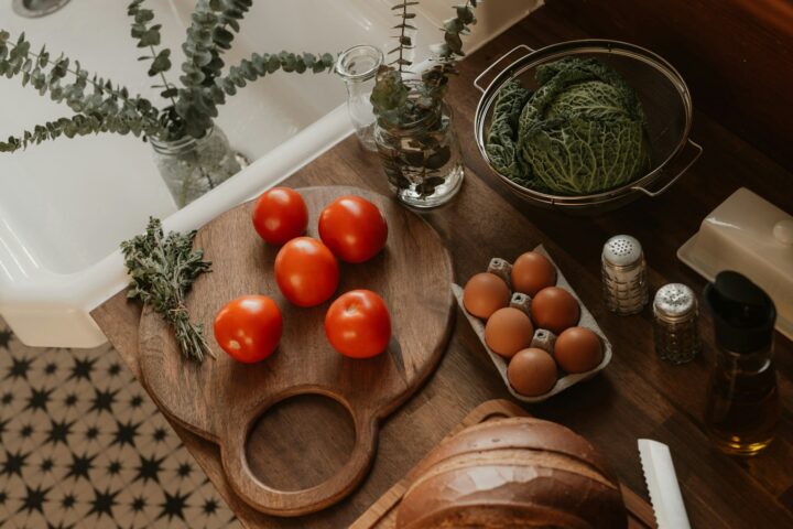 A white bokashi composting bucket sitting on a kitchen counter with a wooden spoon beside it.