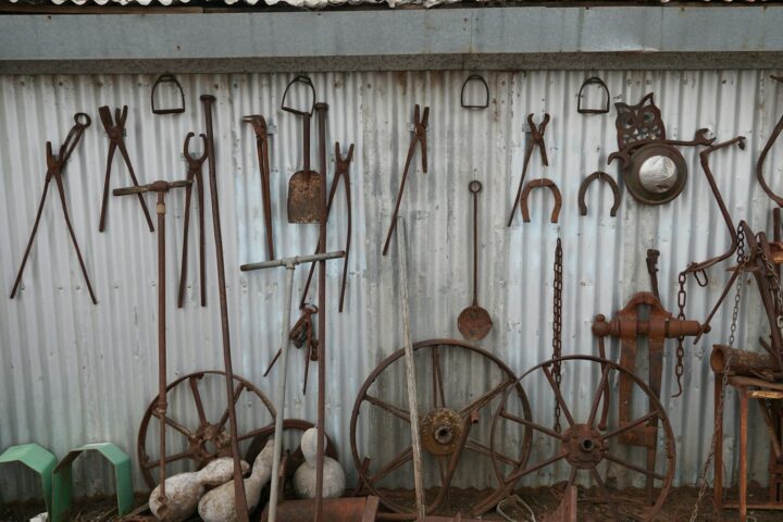 A tidy row of garden tools hanging on a shed wall, with a few unused implements standing in the corner.
